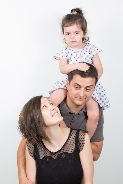 Heureuse jeune famille maman papa et petite fille Les parents gardent la fille dans les épaules