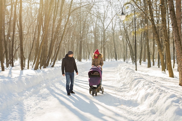 Heureuse jeune famille marchant dans le parc en hiver.