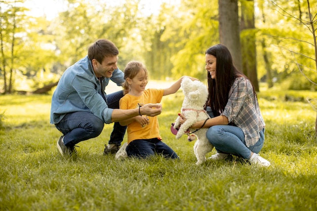 Heureuse jeune famille avec mignon chien bichon dans le parc