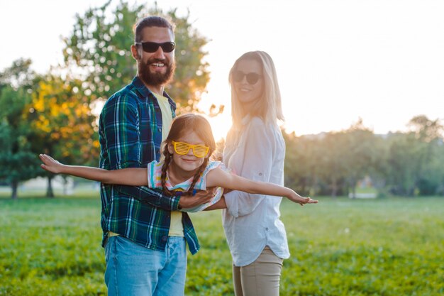 Heureuse jeune famille, passer du temps ensemble à l'extérieur dans la nature verdoyante.