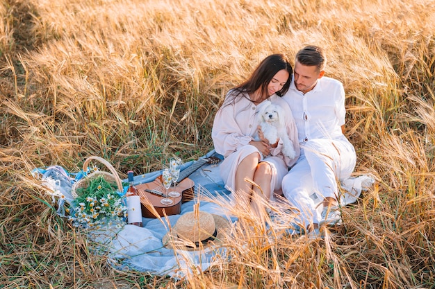 Heureuse jeune famille en pique-nique dans un champ de blé jaune