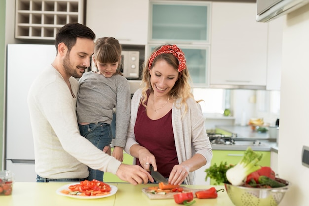 Heureuse jeune famille préparant le déjeuner dans la cuisine