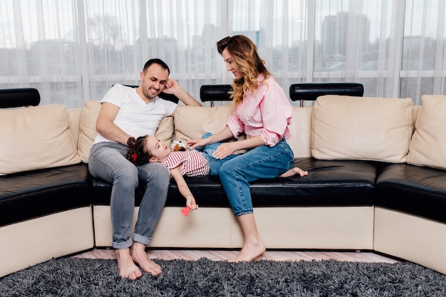 Heureuse jeune famille restant à la maison. famille appréciant un moment tendre,