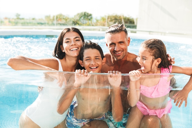 Heureuse jeune famille s'amusant à l'intérieur d'une piscine