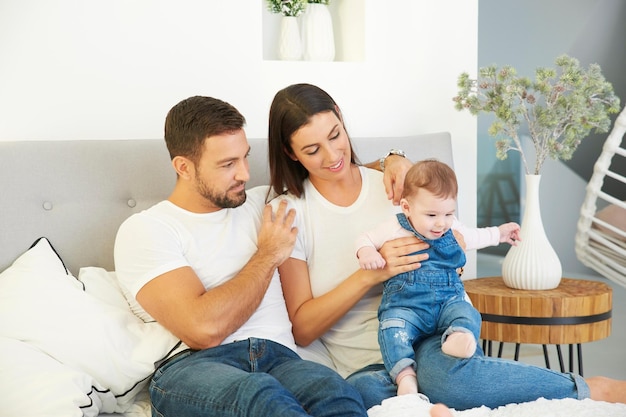 Heureuse jeune famille se détendre au lit avec leur petite fille