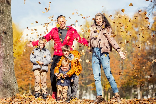 Heureuse jeune famille avec trois enfants dans le parc en automne. Amour et tendresse. Marchez dans la saison dorée.