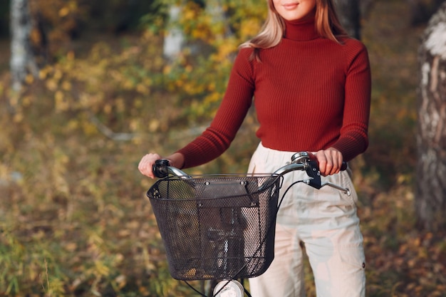 Heureuse jeune femme active faisant du vélo dans le parc d'automne