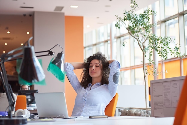 Photo heureuse jeune femme d'affaires avec une coiffure bouclée dans le bureau moderne