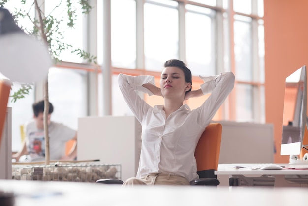 heureuse jeune femme d'affaires se détendre et s'inspirer tout en travaillant sur un ordinateur de bureau à l'intérieur d'un bureau moderne et lumineux