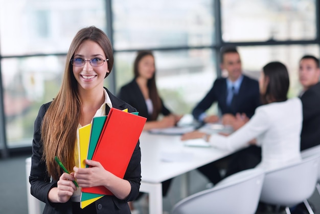 heureuse jeune femme d'affaires avec son personnel, groupe de personnes en arrière-plan dans un bureau moderne et lumineux à l'intérieur