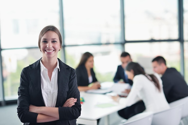 heureuse jeune femme d'affaires avec son personnel, groupe de personnes en arrière-plan dans un bureau moderne et lumineux à l'intérieur