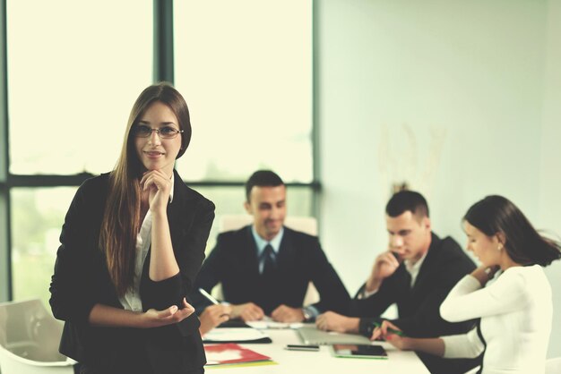 heureuse jeune femme d'affaires avec son personnel, groupe de personnes en arrière-plan dans un bureau moderne et lumineux à l'intérieur