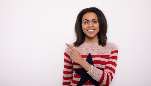 Heureuse jeune femme africaine présentant sur mur blanc