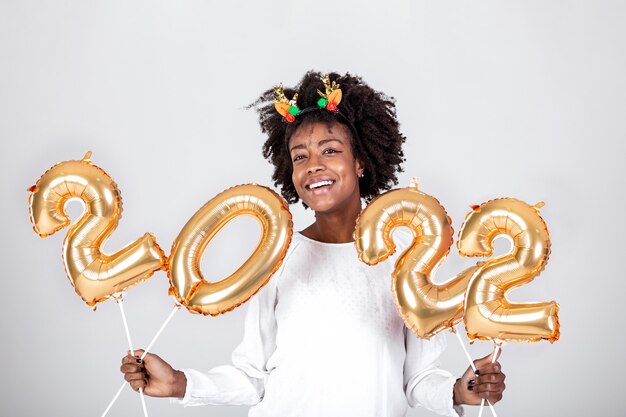 Heureuse jeune femme afro-américaine tenant des ballons de couleur or 2022