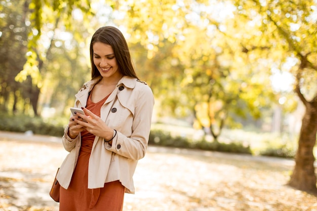 Heureuse jeune femme à l&#39;aide de téléphone portable en automne parc