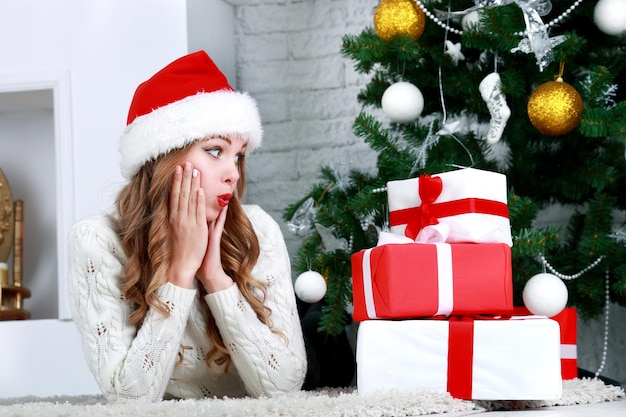 Heureuse jeune femme allongée sur le sol avec boîte-cadeau de noël