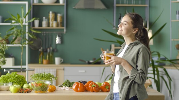 Heureuse jeune femme appréciant le jus fraîchement pressé à l'aide de produits biologiques