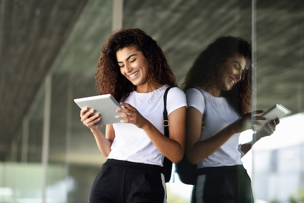 Heureuse jeune femme arabe à l&#39;aide de tablette numérique dans des affaires.