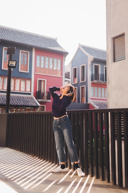 Heureuse jeune femme asiatique écoutant de la musique et s'amusant avec des écouteurs dans la rue