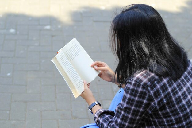 heureuse jeune femme asiatique étudiante lisant un livre dans le concept d'éducation du parc