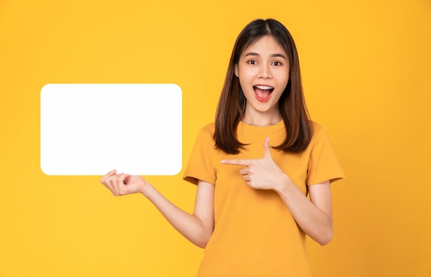 Photo heureuse jeune femme asiatique tenant un papier vierge avec un visage souriant et regardant le fond orange. pour les enseignes publicitaires.