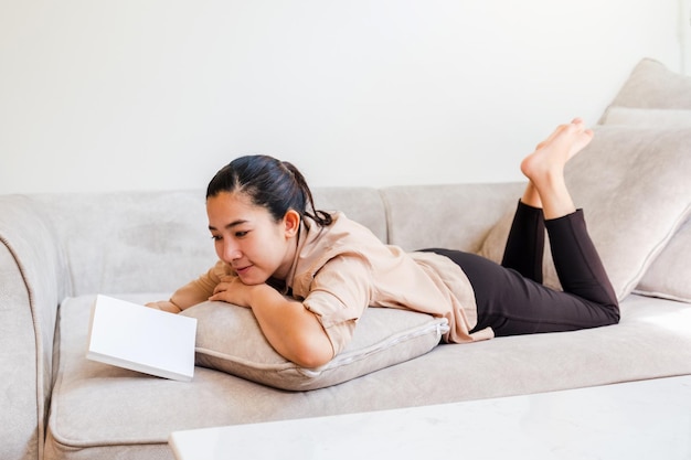 Heureuse jeune femme asiatique travaille à domicile en lisant un livre