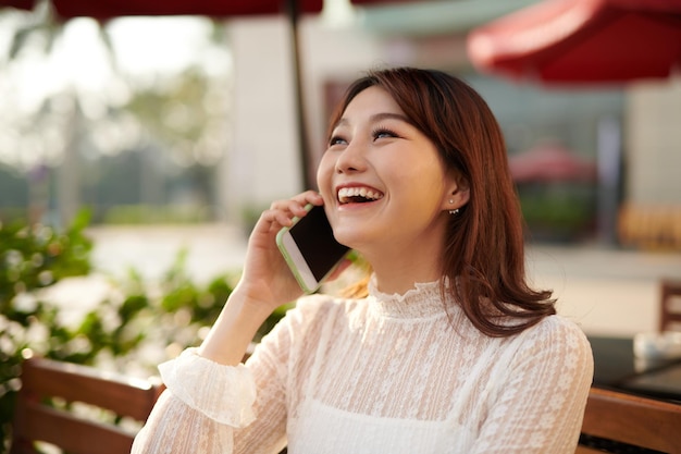 Heureuse jeune femme asiatique de voyage parlant avec un téléphone portable et se détendre