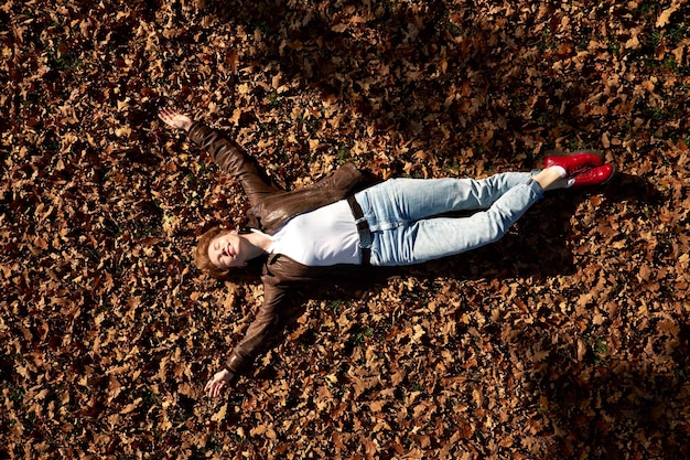 Heureuse jeune femme assez drôle avec les yeux fermés allongé sur le sol en automne parc et détente.