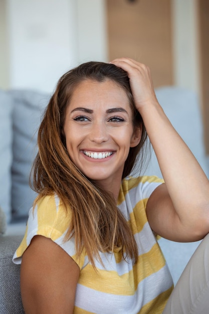 Heureuse jeune femme assise sur un canapé à la maison et regardant la caméra Portrait d'une belle femme souriante et relaxante pendant l'été