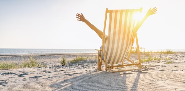 heureuse jeune femme assise sur une chaise de plage sur la plage en été, espace de copie pour votre texte individuel, taille de la bannière