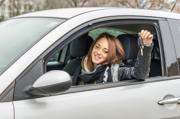 Heureuse jeune femme assise dans la voiture en souriant