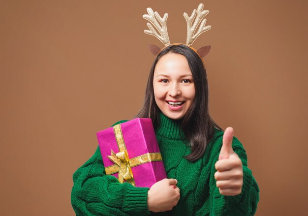 Heureuse jeune femme au chapeau de Noël avec cadeau sur beige