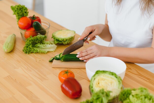 Heureuse jeune femme au foyer, mélange de salade de légumes