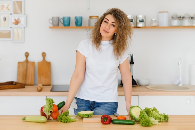 Heureuse jeune femme au foyer, mélange de salade de légumes