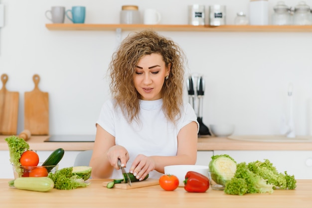 Photo heureuse jeune femme au foyer, mélange de salade de légumes