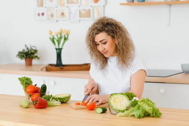 Heureuse jeune femme au foyer, mélange de salade de légumes