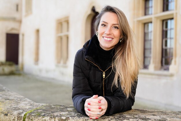 Heureuse jeune femme aux cheveux longs blonds touriste posant dans les rues anciennes