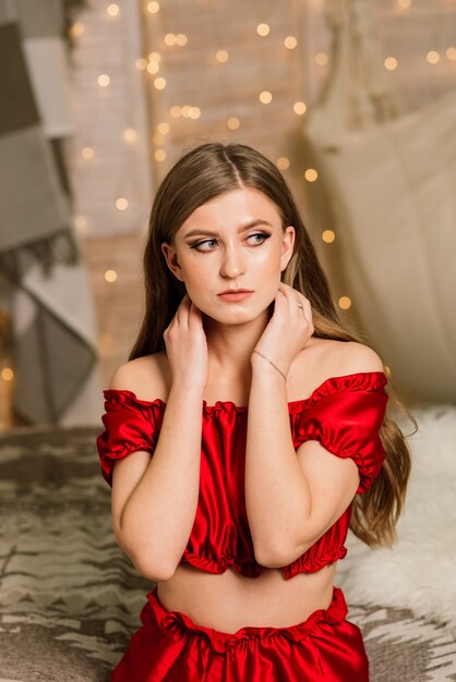 Heureuse jeune femme aux cheveux longs près de la cheminée et du sapin de Noël, cadeaux. Notion de nouvel an.