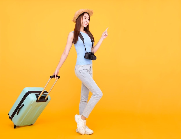 Heureuse jeune femme avec bagages et appareil photo isolé sur fond jaune concept de voyage d'été