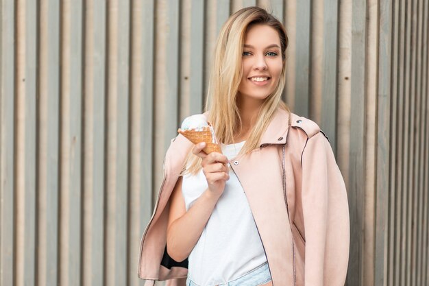 Heureuse jeune femme belle avec un sourire dans une veste rose tient une glace