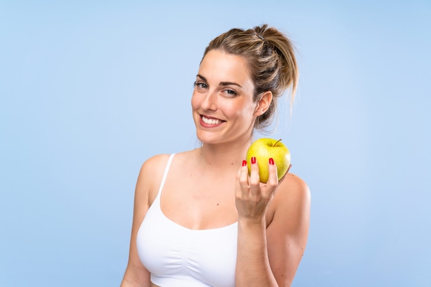 Heureuse jeune femme blonde avec une pomme