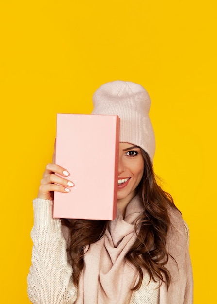 Heureuse jeune femme avec une boîte-cadeau dans ses mains couvre la moitié de h