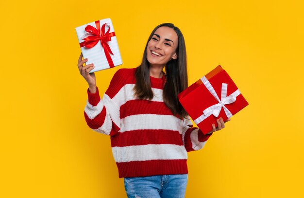 Heureuse jeune femme brune excitée avec une boîte-cadeau en mains isolées sur fond jaune