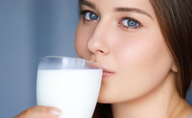 Heureuse jeune femme buvant du lait ou un cocktail de milk-shake protéiné boisson saine pour l'alimentation et le bien-être