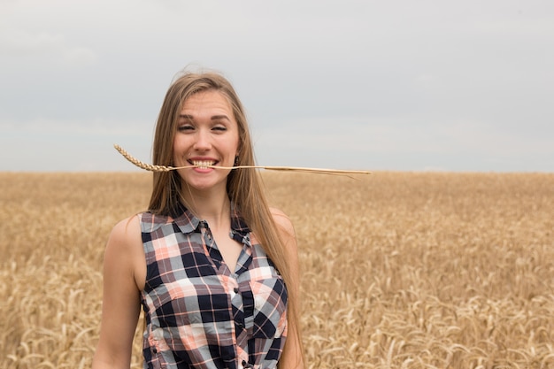 Heureuse jeune femme dans le champ de blé doré