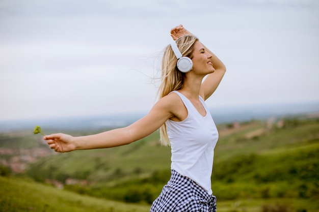 Heureuse jeune femme dans la nature, écouter de la musique sur les écouteurs