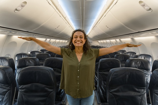 Heureuse jeune femme debout dans l'allée de l'avion