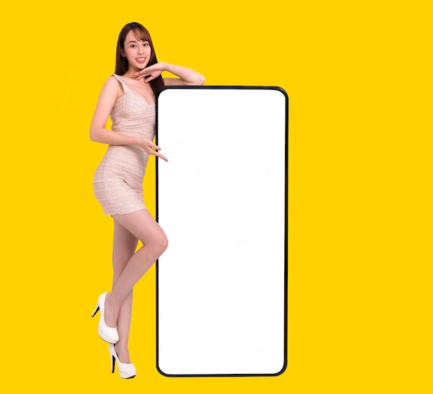 Heureuse jeune femme debout et se penchant gros Smartphone avec écran blanc vierge