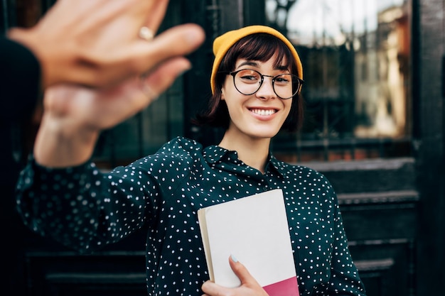 Heureuse jeune femme donnant cinq à un ami lors d'une collaboration amicale sur un projet d'étude