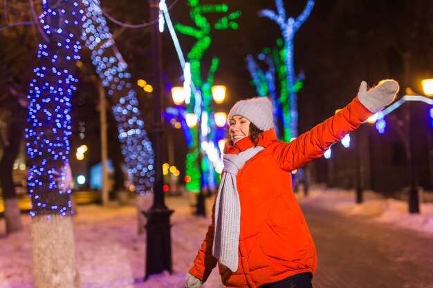 Heureuse jeune femme drôle avec des vêtements d'hiver fond soirée lumières de la ville illumination noël